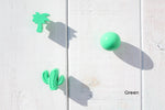 Green cactus-shaped hooks on a white panelled wall. Green Cabinet Knobs. Green Palm Tree Wall Hook. Green Sphere Wall Hook. Green Palm Tree Drawer Pull. Glossy Green Round Door Handle. Green Cactus Drawer Pulls.